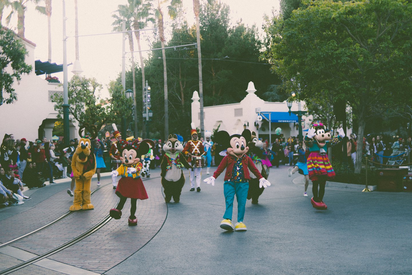 Costumed characters walk down a brick street during a parade.