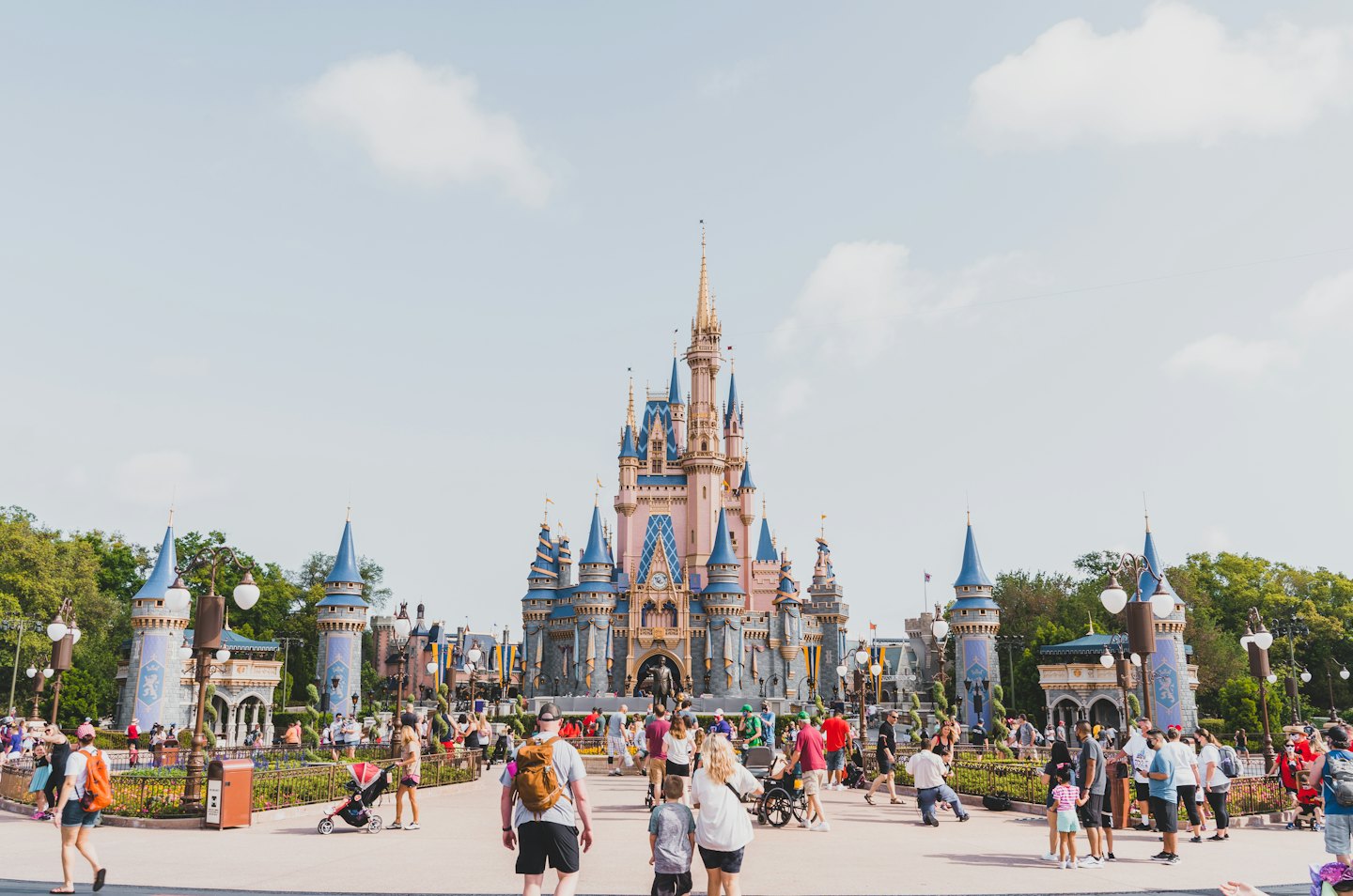 Visitors walk past a fairytale castle with blue turrets.
