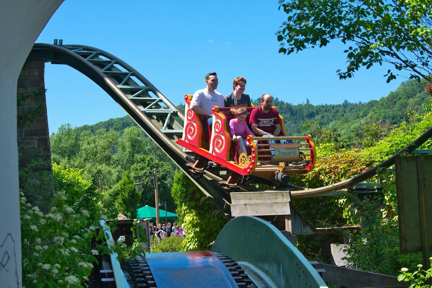 Family rides a red and gold log flume roller coaster.